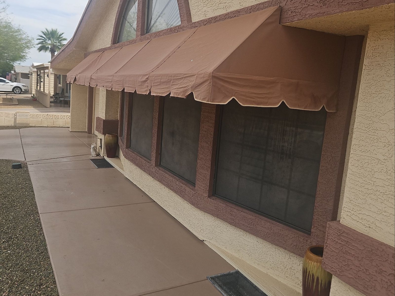 Grey, hazy window sunscreens under an awning on a Sun Lakes commercial property