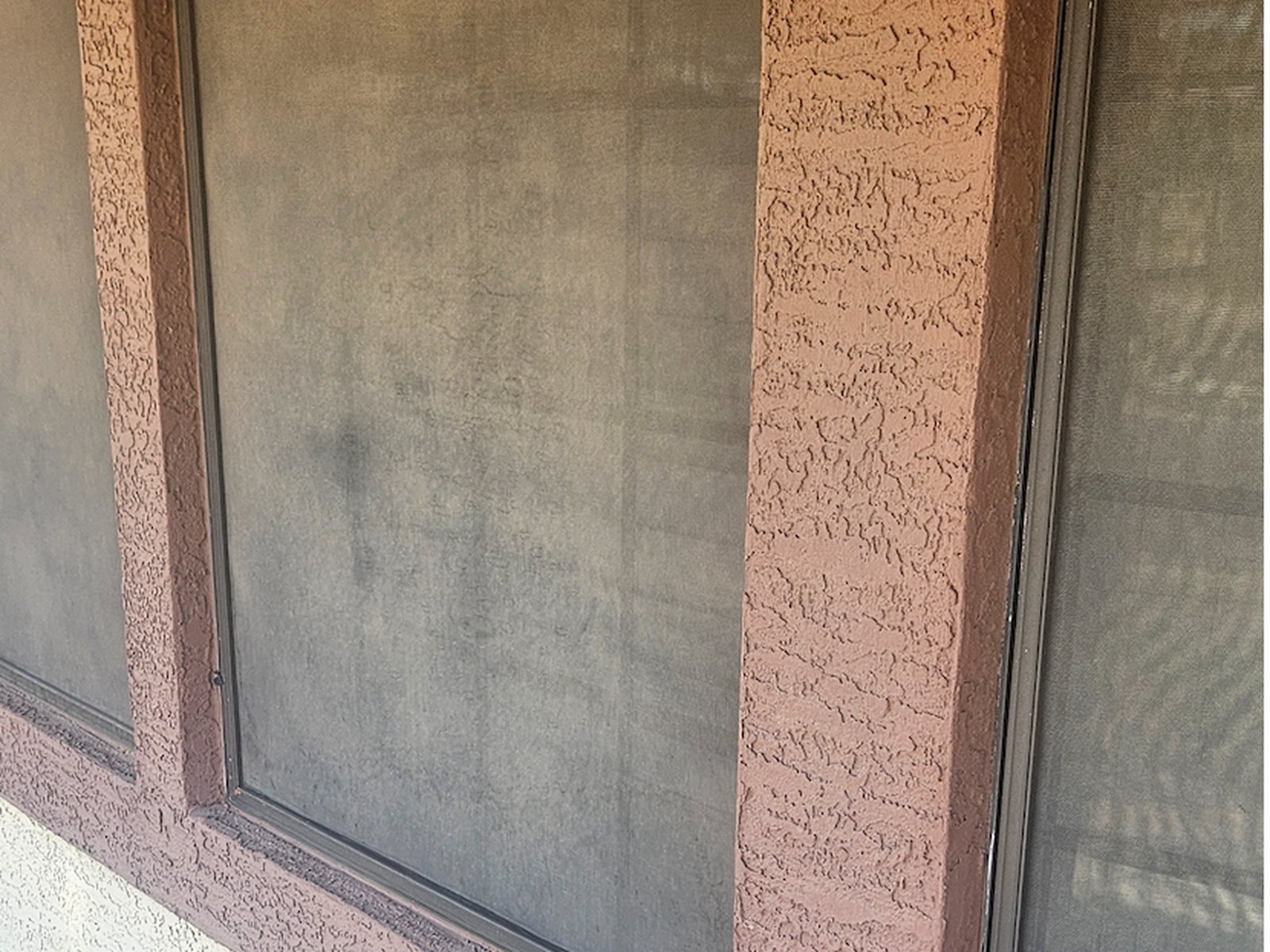 Hazy window sunscreen beside a stucco column on a Sun Lakes commercial property